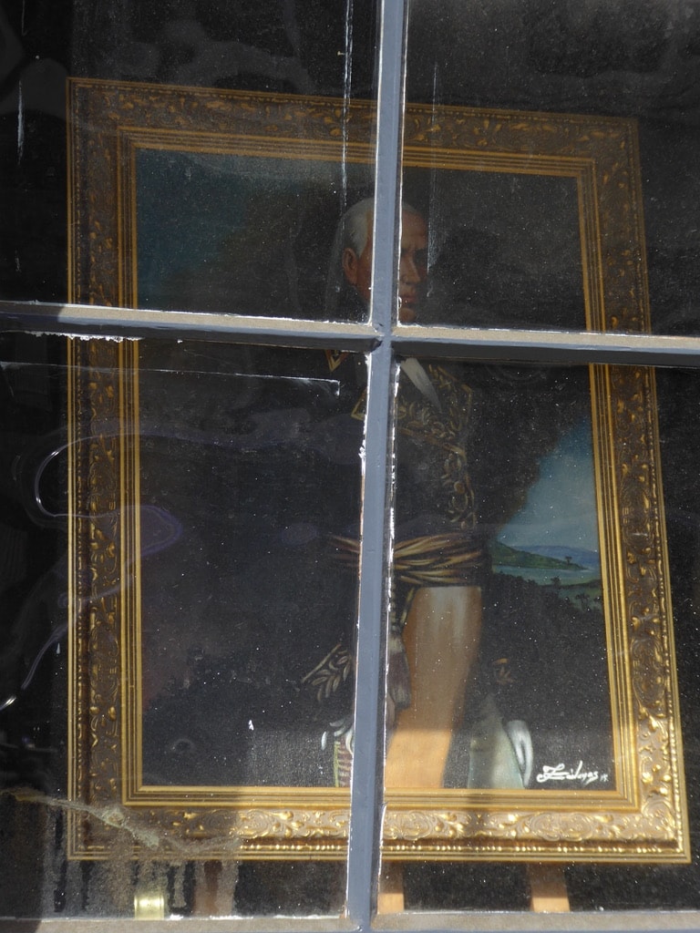 Ornate gold-framed portrait through a pub window